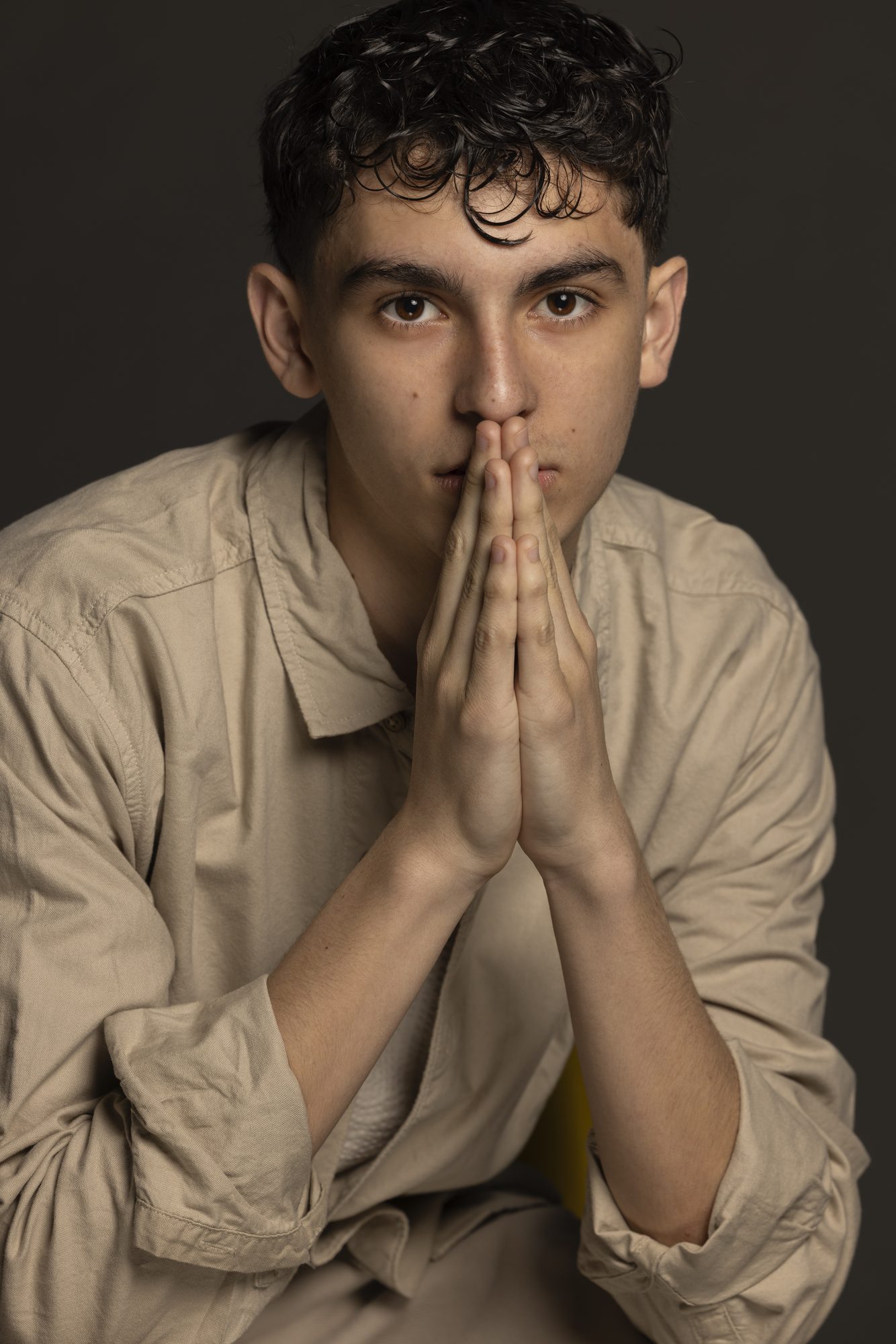 Nicolás Devoto seated with hands pressed together, studio portrait